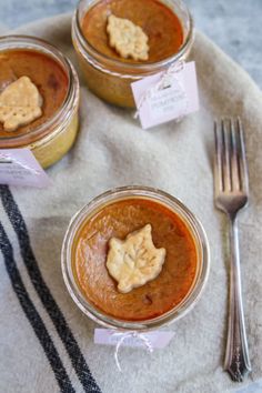 three jars filled with different types of food on top of a table next to a fork