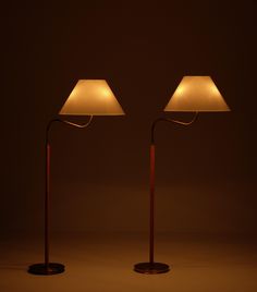 two floor lamps sitting next to each other on a dark surface with one lamp turned off