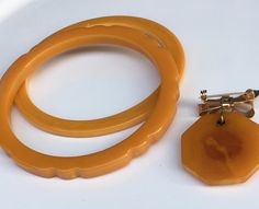 Vintage yellow mustard Bakelite jewelry set.. two spacer bangle one is plain the other one has a scallop carved,And a dangling dog brooch From circa 1950's Retro Handmade Bangle Jewelry, Mid-century Handmade Formal Jewelry, Mid-century Handmade Wedding Jewelry, Vintage Amber Bangle Jewelry, Vintage Bakelite Bracelet, Mid-century Yellow Gold Brooch Jewelry, Mid-century Bracelet Jewelry Gift, Collectible Vintage Amber Jewelry, Adjustable Vintage Amber Jewelry