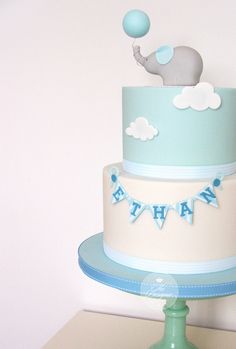 a blue and white cake with an elephant topper on it's tiers