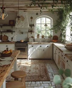 an old fashioned kitchen with stone floors and white cabinets, potted plants on the wall