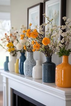 vases filled with flowers sitting on top of a mantle