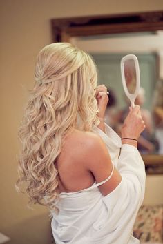 a woman is looking at her reflection in the mirror while brushing her hair with a brush