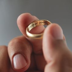 a person holding a gold ring with the words forever you on it