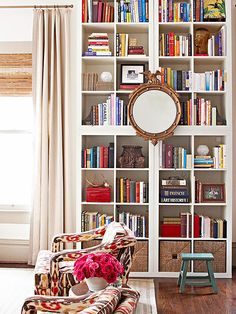 a living room filled with lots of furniture and bookshelves covered in colorful books