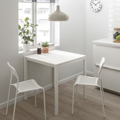 a white table with two chairs and a clock on the wall