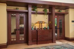 a living room with wooden furniture and green plants on the shelf above it's doors