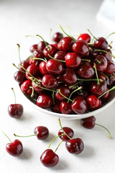 a white bowl filled with cherries on top of a table