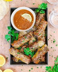 chicken wings with dipping sauce on a white platter next to a glass of water