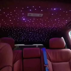 the interior of a car with stars on the ceiling and red leather seats in front