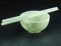 a bowl with chopsticks in it sitting on a black table next to another bowl