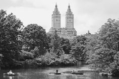 black and white photograph of two people in rowboats on the river with tall buildings in the background