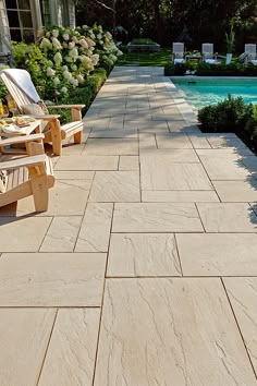 an outdoor patio with chairs next to a swimming pool