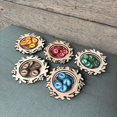 four wooden bowls with buttons in them sitting on a table