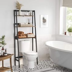 a white bath tub sitting next to a wooden shelf filled with towels and other items