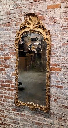 an ornate gold framed mirror on a brick wall