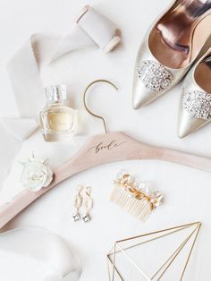 wedding accessories laid out on top of a white cloth and wooden hanger with the bride's shoes