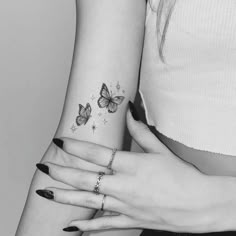 two women's hands with tattoos on their fingers and one has a butterfly tattoo