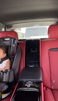 a baby sleeping in a car seat next to an electronic device on the back of a vehicle