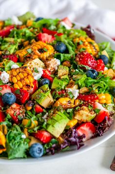 a colorful salad on a white plate with blueberries and corn