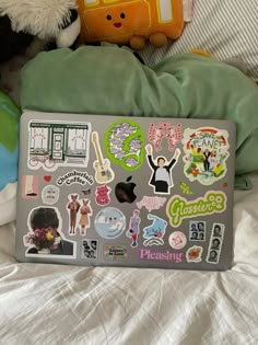 a laptop computer sitting on top of a bed covered in lots of sticker sheets