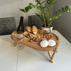 a wooden tray topped with food next to a potted plant and two vases