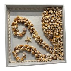 the word sea spelled out with seashells and starfish in a shadow box