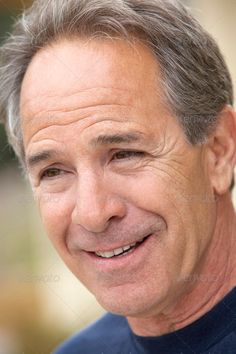 an older man with gray hair smiles at the camera while wearing a blue shirt - stock photo - images