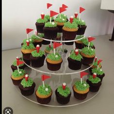 cupcakes with green frosting and red flags are arranged on a cake stand