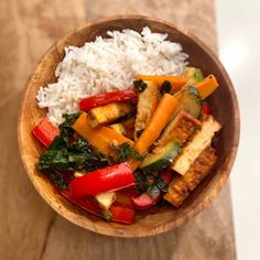 a wooden bowl filled with rice and vegetables