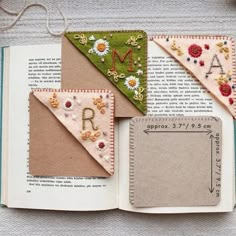 an open book that has some fabric on top of it with letters and flowers in the pages