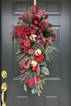 a christmas wreath on the front door with bells and pine cones hanging from it's side