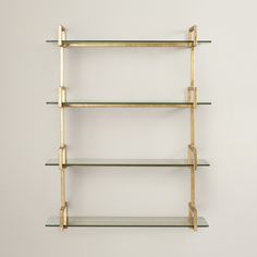 a shelf with glass shelves on each side and gold brackets at the top, against a white wall