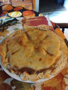 a pie sitting on top of a white plate next to a knife and fork,