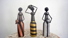 three metal figurines sitting on top of a table next to an empty bottle