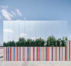 a colorful striped wall with trees in the background