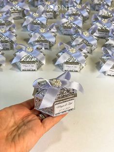 someone is holding a small gift box in front of many smaller boxes with bows on them