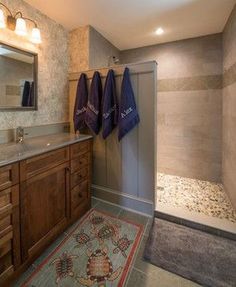 a bathroom with two towels hanging on the wall and a rug in front of it