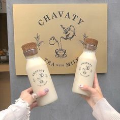 two women holding up bottles of milk in front of a sign that says chavaty tea with milk