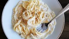 a white plate topped with pasta covered in sauce and sprinkled with seasoning