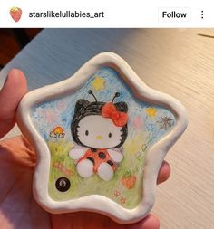 someone is holding up a hello kitty ornament in their left hand, with the image of a ladybug on it