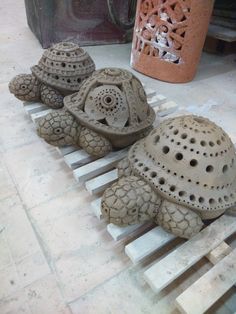 three clay turtles sitting on top of wooden pallets