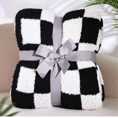 a black and white checkered blanket with a bow on it sitting on a couch