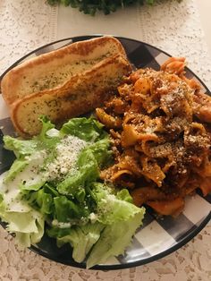 a plate filled with pasta, bread and lettuce on top of a table