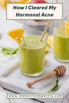 two glasses filled with green smoothie next to sliced fruit