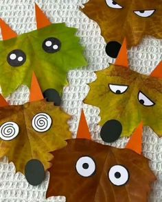 four leaf shaped animals with eyes and noses are on a white surface, surrounded by orange leaves