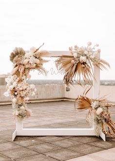 an arch decorated with dried flowers and foliage for a wedding ceremony on the roof of a building