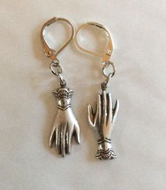 A pair of mixed matched elegant hands two hand earrings created from two Victorian styled findings raw brass gold tone charms For pierced ears with leverback fittings Perhaps a present for an engagement or wedding with the emphasis on hands in both celebrations.  Please note that the hands are identical and therefore not a true 'pair' of hands.  These earrings hang one from the fingers, and the other hangs from the cuff, so it is like giving someone a hug I also have earrings that both hang from the fingers, or a pair that both hang from the cuffs in a choice of metals The charms are single sided stamped metal and are therefore hollow backed and lovely and light to wear Measurement hand 2.5cm long each  See other hand face and eye jewellery Hand Cast Silver Dangle Earrings, Silver Hand Cast Dangle Earrings, Silver Brass Jewelry With Lobster Clasp, Hand Cast Silver Drop Earrings, Silver Hand Cast Drop Earrings, Hand Cast Metal Jewelry For Weddings, Metal Charms Jewelry For Wedding, Adjustable Lever Back Jewelry Gift, Adjustable Lever Back Jewelry As A Gift