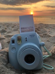 a polaroid camera sitting in the sand with an image on it's back