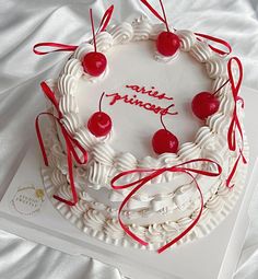 a white cake decorated with cherries and ribbons on top of a card that says ann frisbee